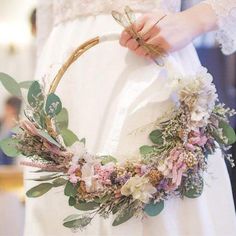 a woman is holding a flower wreath in her hand