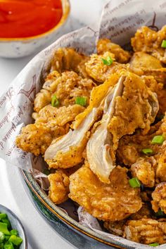 fried chicken with green onions and sauce in a bowl on a table next to some chopsticks