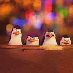 three little penguins are standing in the sand