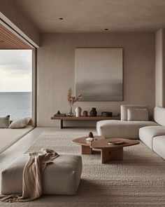 a living room filled with furniture and a large window overlooking the ocean in front of it