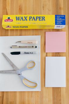 some craft supplies are laying out on a wooden table with paper, scissors and glue