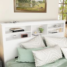 a bed with two pillows on top of it and a painting above the headboard