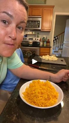 a woman sitting at a kitchen counter with a plate of macaroni and cheese