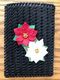 a crocheted square with poinsettis and leaves on it sitting on a wooden surface