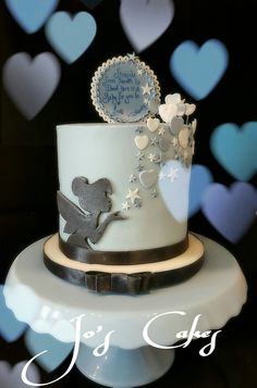 there is a white cake with silver decorations on the top and blue hearts in the background