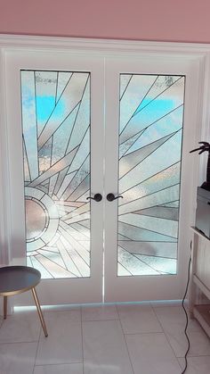 two glass doors in the corner of a room with a table and chair next to them