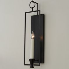 a candle is lit on the wall next to a mirror with a light inside it