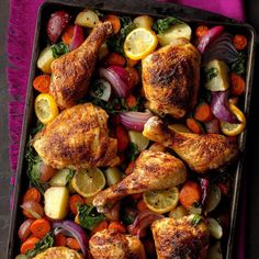 roasted chicken with vegetables and lemons in a baking pan on a purple cloth next to a fork