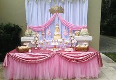 a table with pink tulle skirt and cake on it, sitting in front of a window