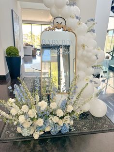 Elegant Baby Boy in Bloom-themed baby shower with white balloons, blue and white floral arrangements, and a gold mirror accent. Perfect decor inspiration for a refined and whimsical celebration. Classy Floral Arrangements, Blue Toile Baby Shower Decor, Spring Boy Baby Shower Ideas, Elegant Baby Shower Ideas For Boys, Blue And White Floral Arrangements, Baby Boy In Bloom, Baby In Bloom Boy, Baby In Bloom Baby Shower Theme, Peter Rabbit Baby Shower Ideas