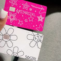 a person holding up a pink and white stargirl credit card in their left hand