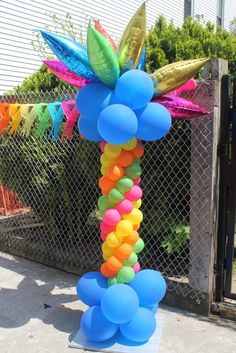 a bunch of balloons are tied to a pole in front of a chain link fence