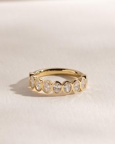 a yellow gold ring with five diamonds on it's side, sitting on a white surface