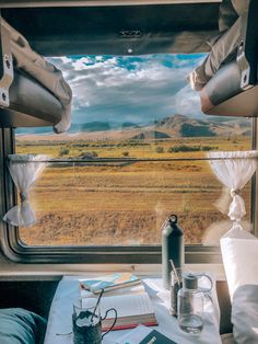 the view from inside a train car looking out at an open field with mountains in the distance