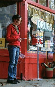 a woman standing in front of a store looking at her cell phone