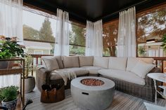 a living room filled with lots of furniture and plants on top of a wooden floor