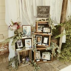 there is a display with pictures and flowers on the outside wall in front of a house