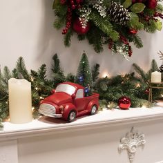 a red truck is parked in front of a mantle with christmas decorations and candles on it