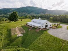 an aerial view of a large white house in the middle of a lush green field