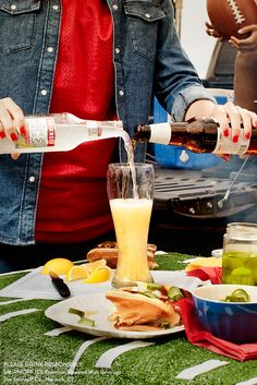 a woman pours a drink from a bottle into a glass at a football game