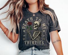 a woman wearing a t - shirt with a skeleton holding a rose