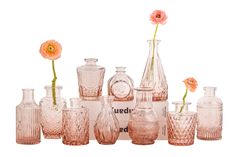 an assortment of pink glass vases and bottles with flowers in them on a white background