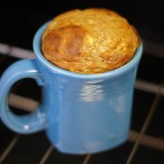 a muffin in a blue mug sitting on top of an oven rack