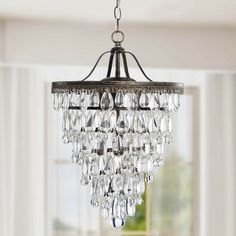 a chandelier hanging from the ceiling in a room with white walls and windows