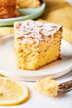 a close up of a piece of cake on a plate with lemons in the background