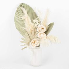 a white vase filled with flowers and feathers