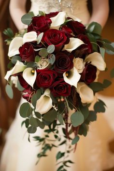 a bride holding a bouquet of red roses and calla lilies on her wedding day