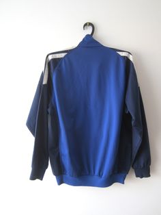 "Vintage Blue Adidas Jacket Blue Adidas Zipper Running Jacket Unisex Jogging Parka Blue Soccer Jacket Three Stripes Size Large Adidas Cardigan Label size: D 176; GB 34/36; F 16A Measurements: (lying flat) Length - 28.5\"/ 72.5 cm Shoulders: 20\"/ 51 cm Pit to pit: 22.5\"/ 57 cm Waist: 19.5\"/ 49.5 cm Sleeve: 22.5\"/ 57 cm Please check measurements to insure a proper fit. Remember to allow yourself some extra room for movement. You can compare these with something from your closet that fits you w Blue Long Sleeve Outerwear With Zipper Closure, Blue Long Sleeve Outerwear With Zipper, Stretch Blue Track Jacket For Fall, Sporty Stretch Blue Outerwear, Blue Sports Outerwear With Zipper Closure, Blue Stretch Winter Track Jacket, Blue Stretch Track Jacket For Winter, Blue Sports Track Jacket With Pockets, Blue Sports Track Jacket With Zipper Closure