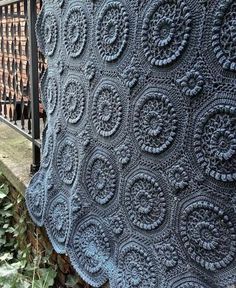 a blue crocheted blanket sitting on top of a fence