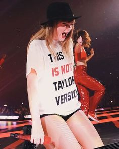 a woman in tights and a t - shirt with words on it is singing into a microphone