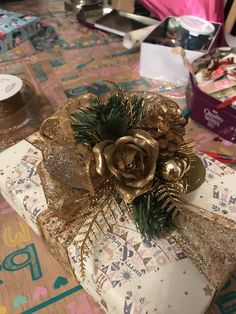 a present wrapped in gold foil and decorated with pine cones is sitting on a table