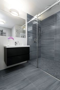 a modern bathroom with gray tile flooring and white walls, along with a walk in shower