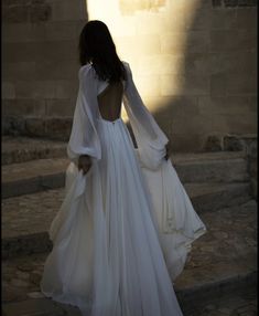 the back of a woman's dress as she walks up some steps with her hands in her pockets