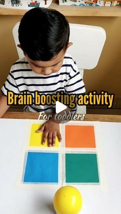 a little boy sitting at a table playing with some sort of color block puzzles