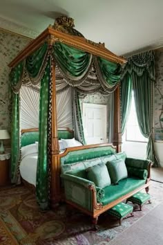 a bedroom with green bedding and curtains on the window sill, an ornate canopy bed