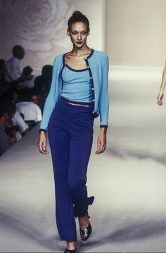 a model walks down the runway in blue pants and a cropped top with an open back