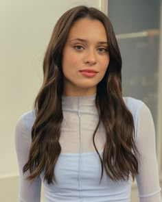 a woman with long brown hair wearing a white top