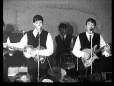 three young men are singing into microphones and playing guitars