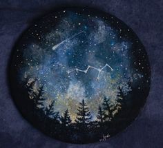 a painted rock with trees on it and the zodiac sign in the sky above them