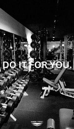 an empty gym with rows of exercise machines and dumbbells in black and white