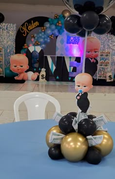 a baby doll is sitting on top of some gold and black balloons at a party