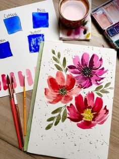 some watercolors are sitting on a table next to paint and paper with flowers