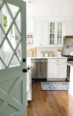 an open door leading to a kitchen with white cabinets