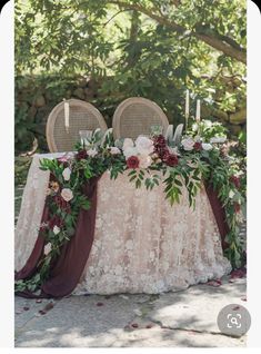 the table is set up with two chairs and flowers on it, along with candles