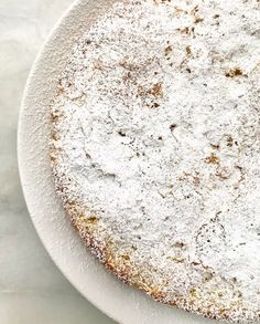 a white plate topped with a cake covered in powdered sugar on top of a table