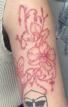 a woman's arm with a flower and mask tattoo on the left side of her arm